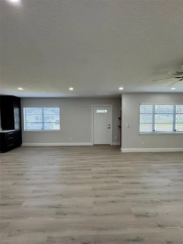 a view of an empty room with wooden floor and a ceiling fan