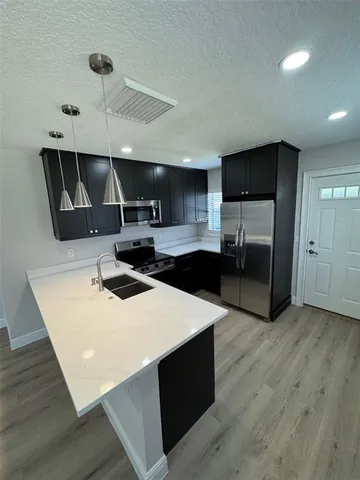 a kitchen with stainless steel appliances a sink a stove a refrigerator and cabinets