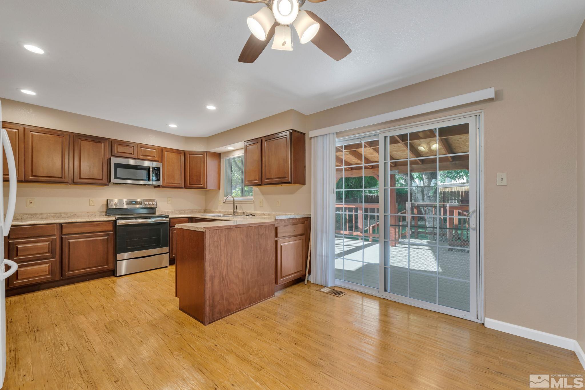3240 Kings Row Reno, NV 89503 - Photo 10 of 31 a large kitchen with a stove a sink dishwasher a kitchen island with cabinets and wooden floor
