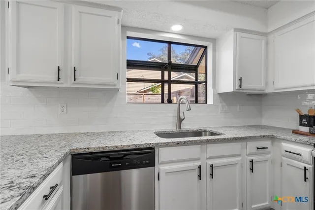 a kitchen with granite countertop a sink cabinets and window