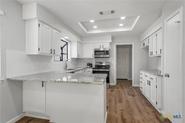 a kitchen with stainless steel appliances granite countertop a refrigerator sink and white cabinets