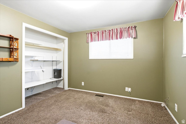 7050 South 260 East Midvale, UT 84047 - Photo 16 of 28 Spacious room featuring neutral carpeting, a window with blinds, and an organized closet with shelving and a hanging rod