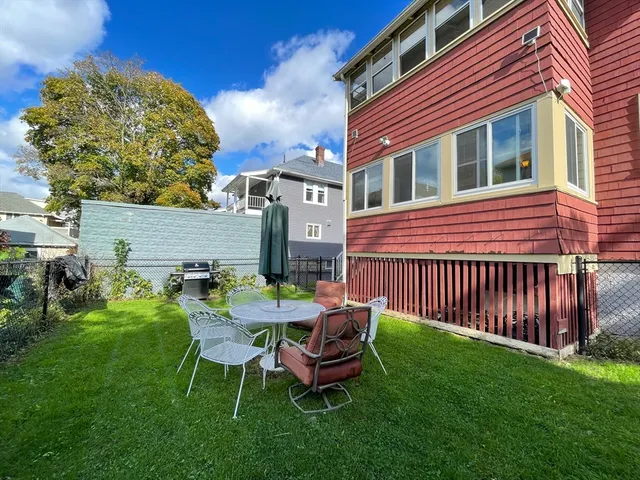 a view of a chair and table in backyard of the house