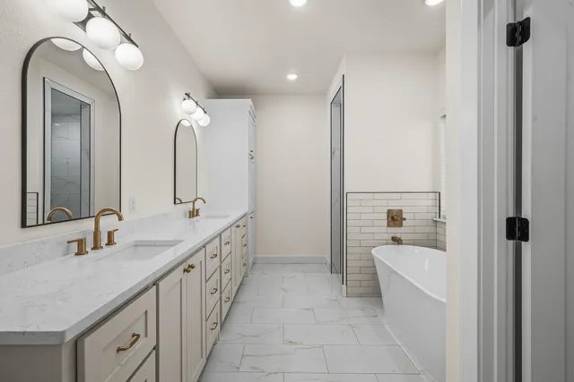 a bathroom with a double vanity sink a mirror and a bathtub