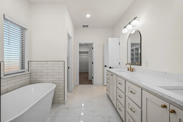 a spacious bathroom with a double vanity sink a large mirror and a bathtub