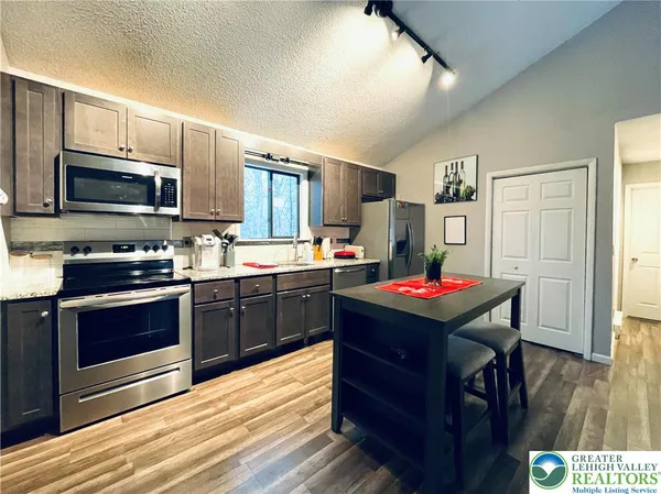 a kitchen with stainless steel appliances kitchen island granite countertop a refrigerator stove and sink