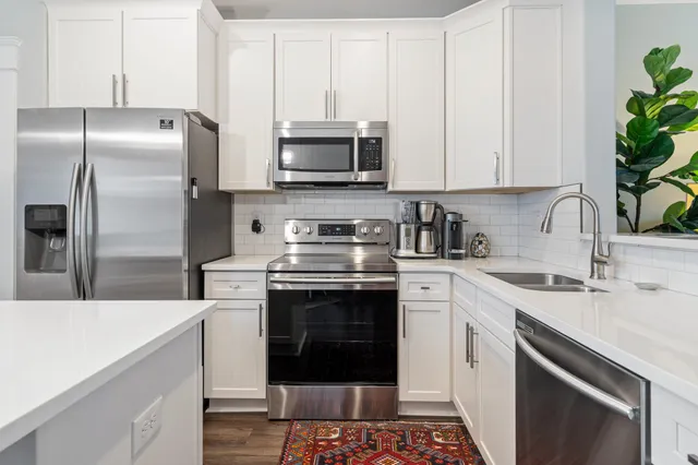 a kitchen with stainless steel appliances a stove a sink a microwave and cabinets