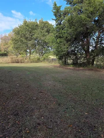 a view of dirt field with large trees