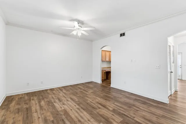 an empty room with wooden floor fan and windows