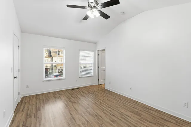 a view of an empty room with a window and wooden floor