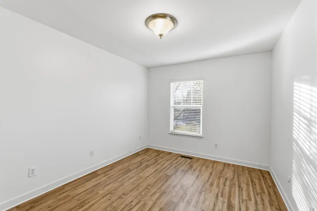an empty room with a window and wooden floor