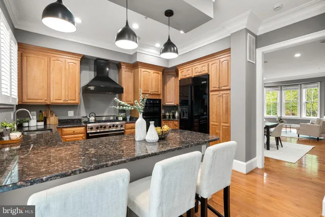 a kitchen with stainless steel appliances granite countertop a stove a sink dishwasher a dining table and chairs with wooden floor