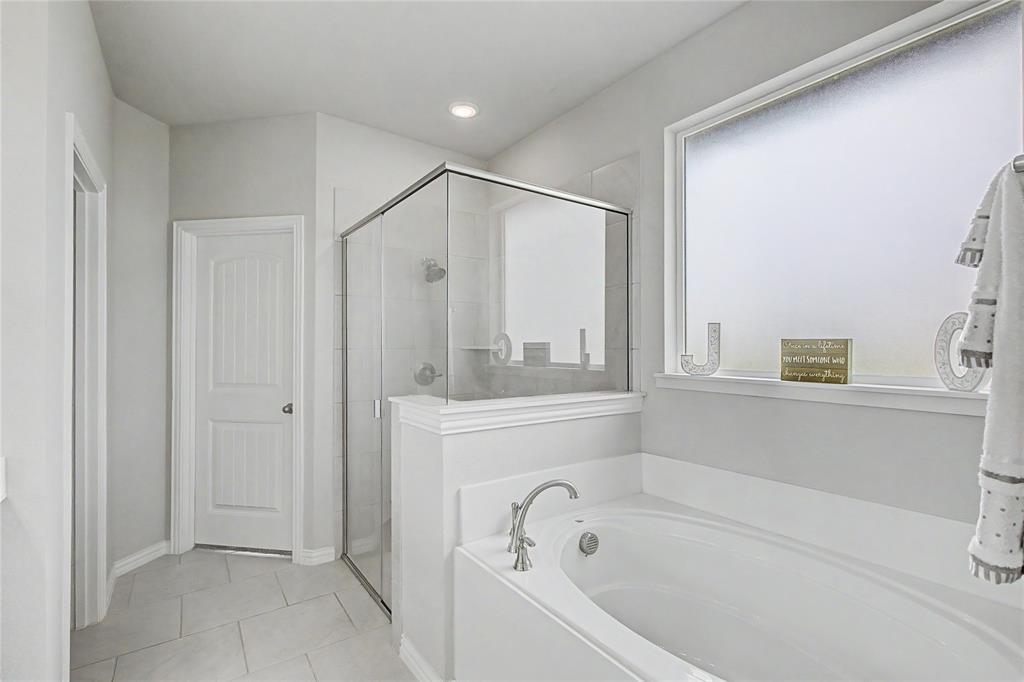 185 Chester Road Springtown, TX 76082 - Photo 25 of 40 Bathroom featuring a standalone soaking tub with brushed nickel fixtures, a glass-enclosed shower, a frosted privacy window, and tile flooring