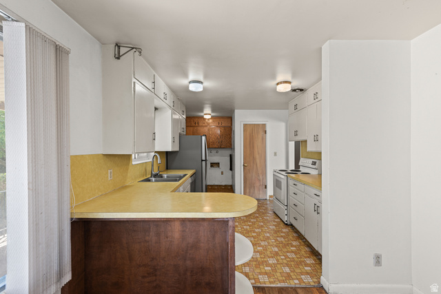 542 East 3400th Street North Provo, UT 84604 - Photo 13 of 39 Kitchen featuring ample white cabinetry, a double basin stainless steel sink, a built-in breakfast bar with a wood-finish base, and integrated ceiling lighting