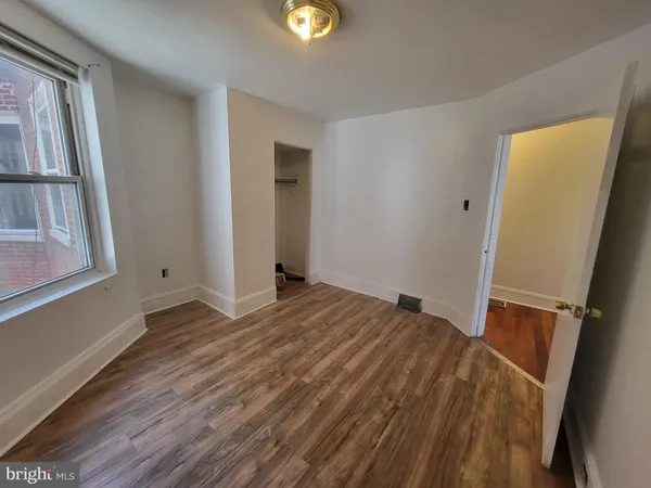 a view of empty room with window and wooden floor