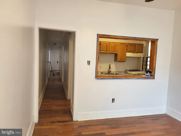 a view of a hallway with wooden floor and a bathroom