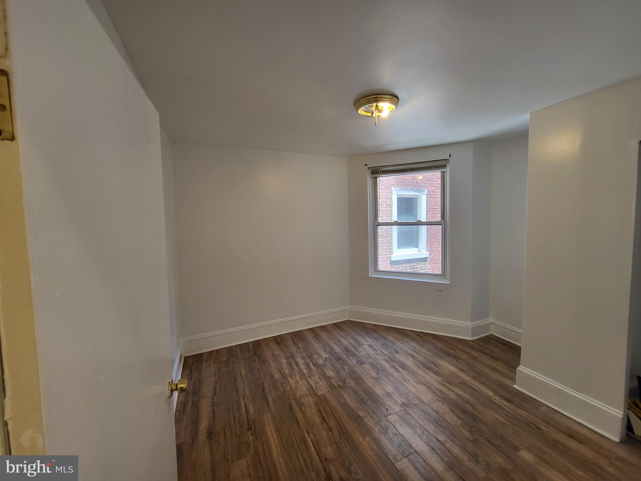 4834 Sansom Street, Unit 1 Philadelphia, PA 19139 - Photo 7 of 23 a view of an empty room with wooden floor and a window