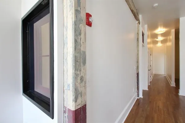 a view of a hallway with wooden floor and cabinet