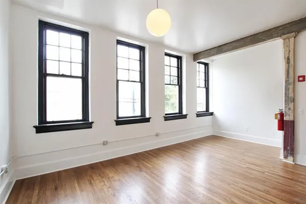 an empty room with wooden floor and windows