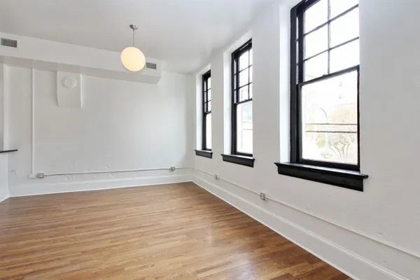 a view of an empty room with wooden floor and a window