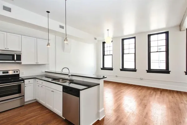 a kitchen with stainless steel appliances granite countertop a sink a stove and cabinets with wooden floor