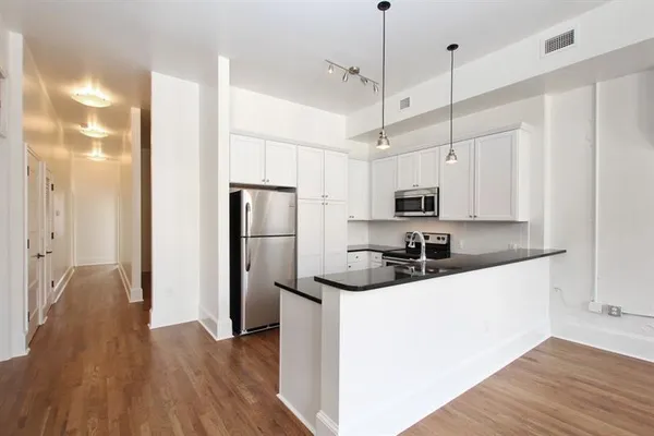 a kitchen with stainless steel appliances a refrigerator a sink dishwasher a stove and white cabinets with wooden floor