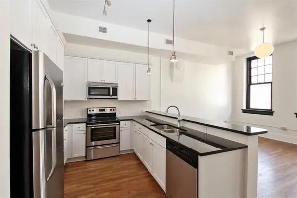 a kitchen with stainless steel appliances granite countertop a sink a stove a refrigerator a center island with wooden floor