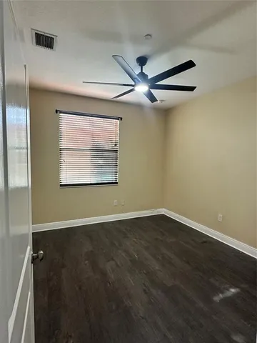 an empty room with wooden floor fan and windows