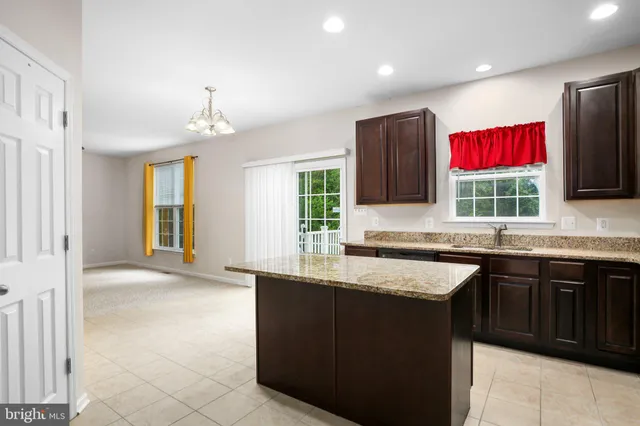 a kitchen with stainless steel appliances granite countertop wooden cabinets a sink a stove a dining table and chairs