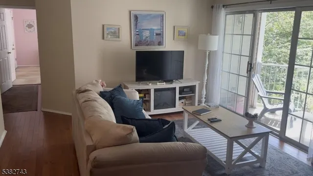 a living room with furniture a flat screen tv and a floor to ceiling window
