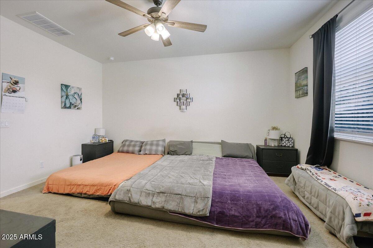 9825 West Trumbull Road Tolleson, AZ 85353 - Photo 9 of 19 a bedroom with two beds and a chandelier