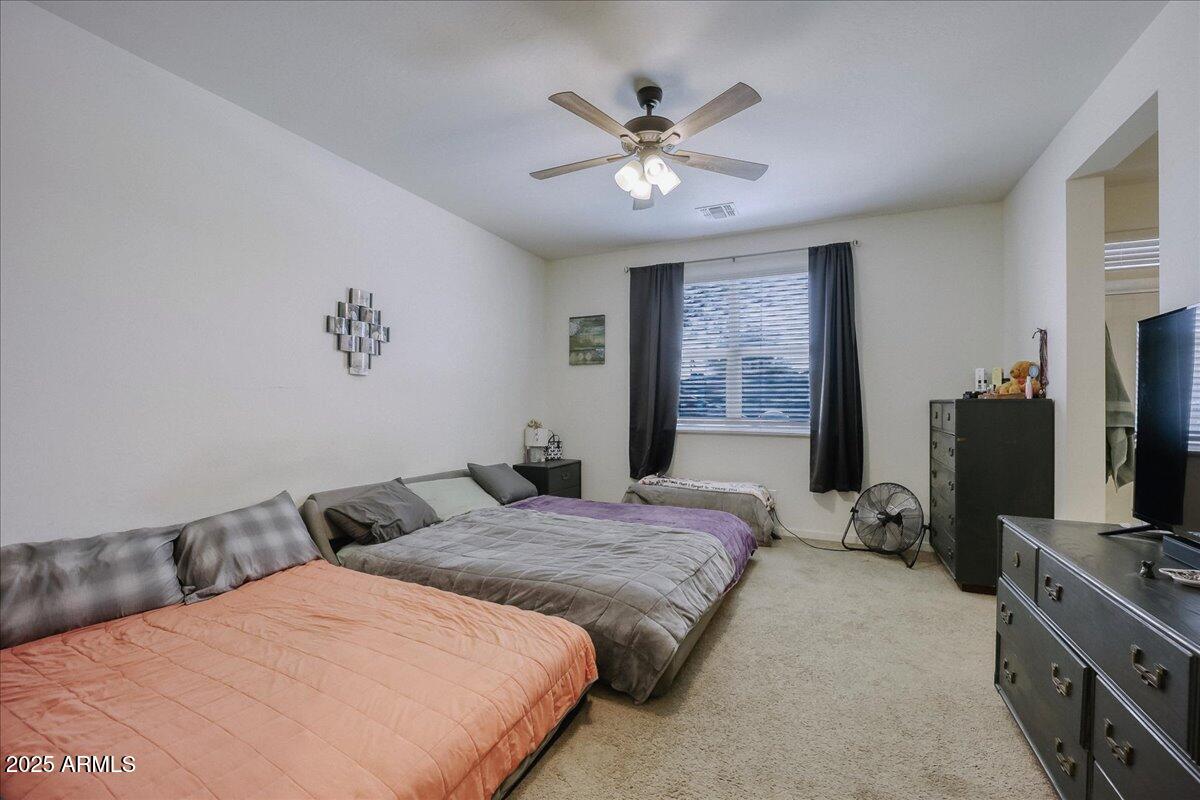 9825 West Trumbull Road Tolleson, AZ 85353 - Photo 10 of 19 a bedroom with a large bed and a flat tv screen on dresser