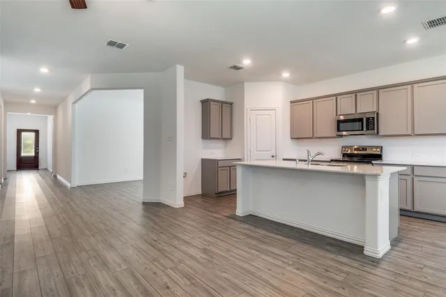 a kitchen with stainless steel appliances granite countertop a refrigerator a stove top oven a sink and dishwasher with wooden floor