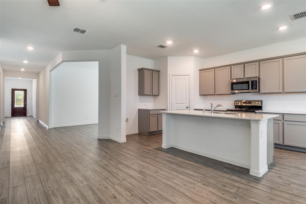 134 Blair Drive Fate, TX 75189 - Photo 4 of 25 a kitchen with stainless steel appliances granite countertop a refrigerator a stove top oven a sink and dishwasher with wooden floor