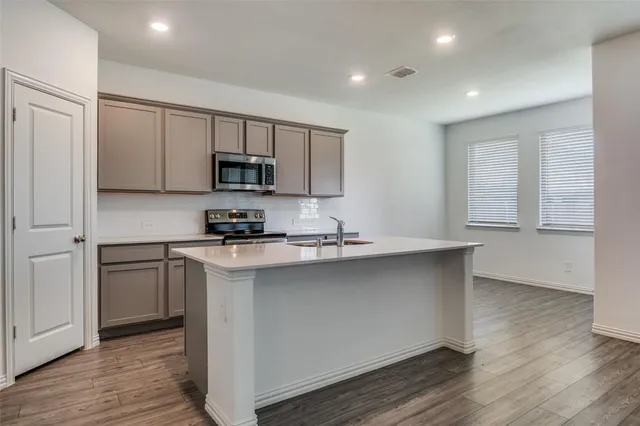 a kitchen with stainless steel appliances granite countertop a stove a sink and a refrigerator
