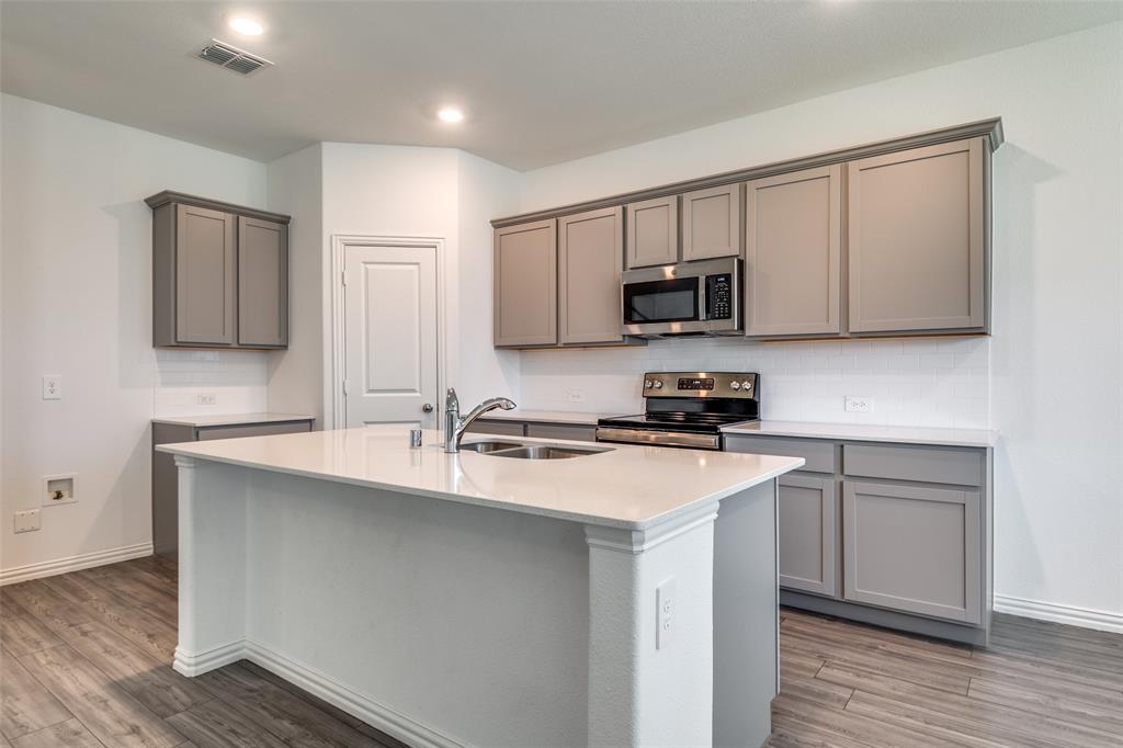134 Blair Drive Fate, TX 75189 - Photo 7 of 25 a kitchen with a sink a stove a microwave and cabinets