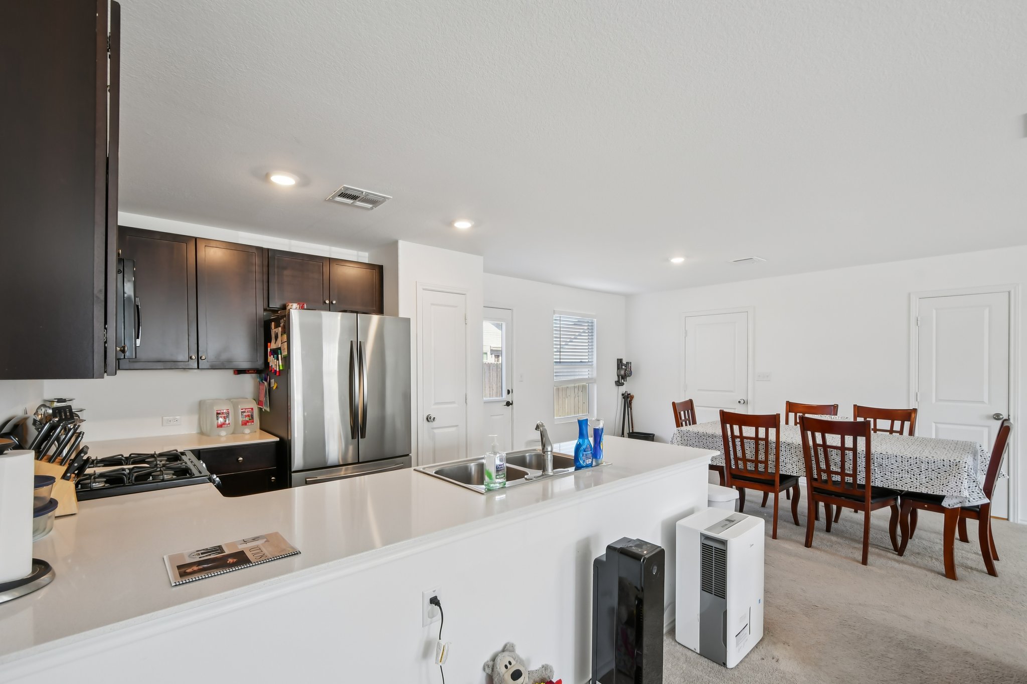 14116 Mussel Run Elgin, TX 78621 - Photo 15 of 40 Kitchen featuring light countertops, stainless steel appliances, a peninsula, dark wood finish cabinets, and light carpet