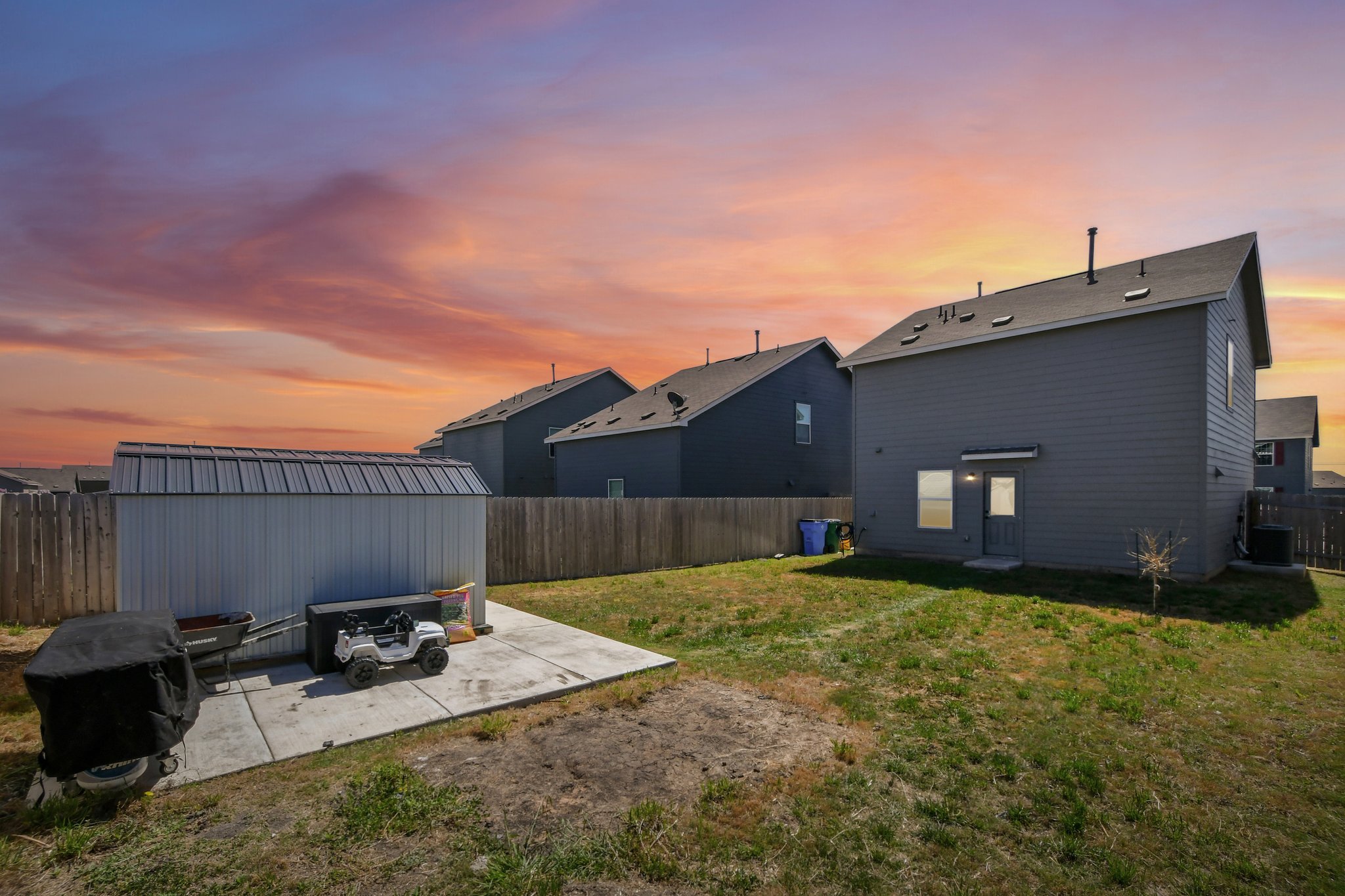 14116 Mussel Run Elgin, TX 78621 - Photo 31 of 40 Back of house at dusk with a fenced backyard, a patio area, and a storage shed