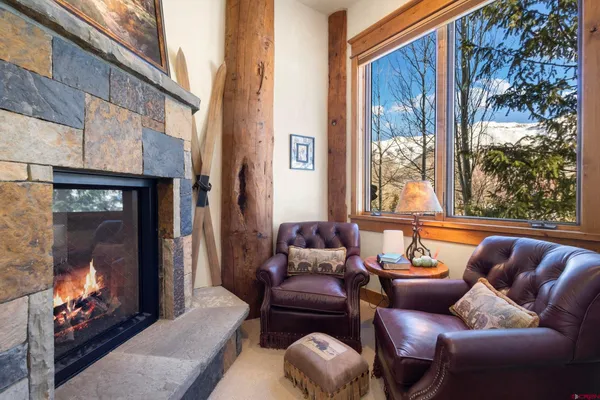 a living room with furniture a fireplace and a floor to ceiling window