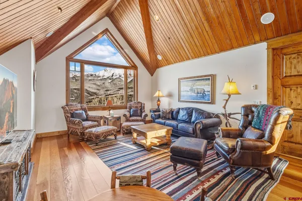 a living room with furniture a large window and wooden floor