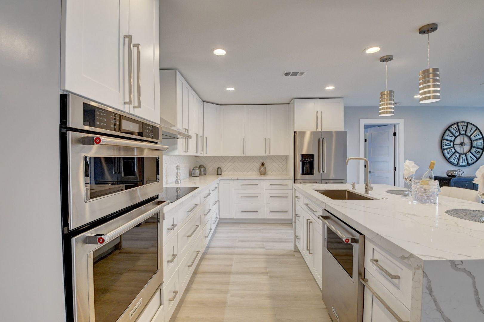 709 Sunshine Drive Delray Beach, FL 33444 - Photo 6 of 25 a kitchen with stainless steel appliances kitchen island granite countertop a stove top oven a sink dishwasher and white cabinets with wooden floor