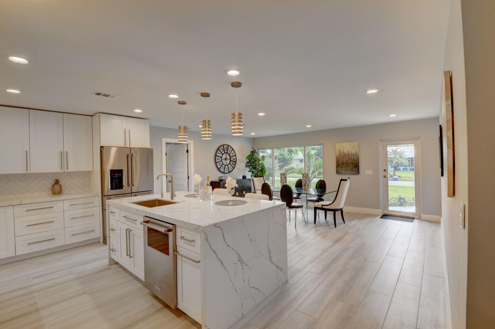 709 Sunshine Drive Delray Beach, FL 33444 - Photo 7 of 25 a kitchen with a dining table chairs and refrigerator