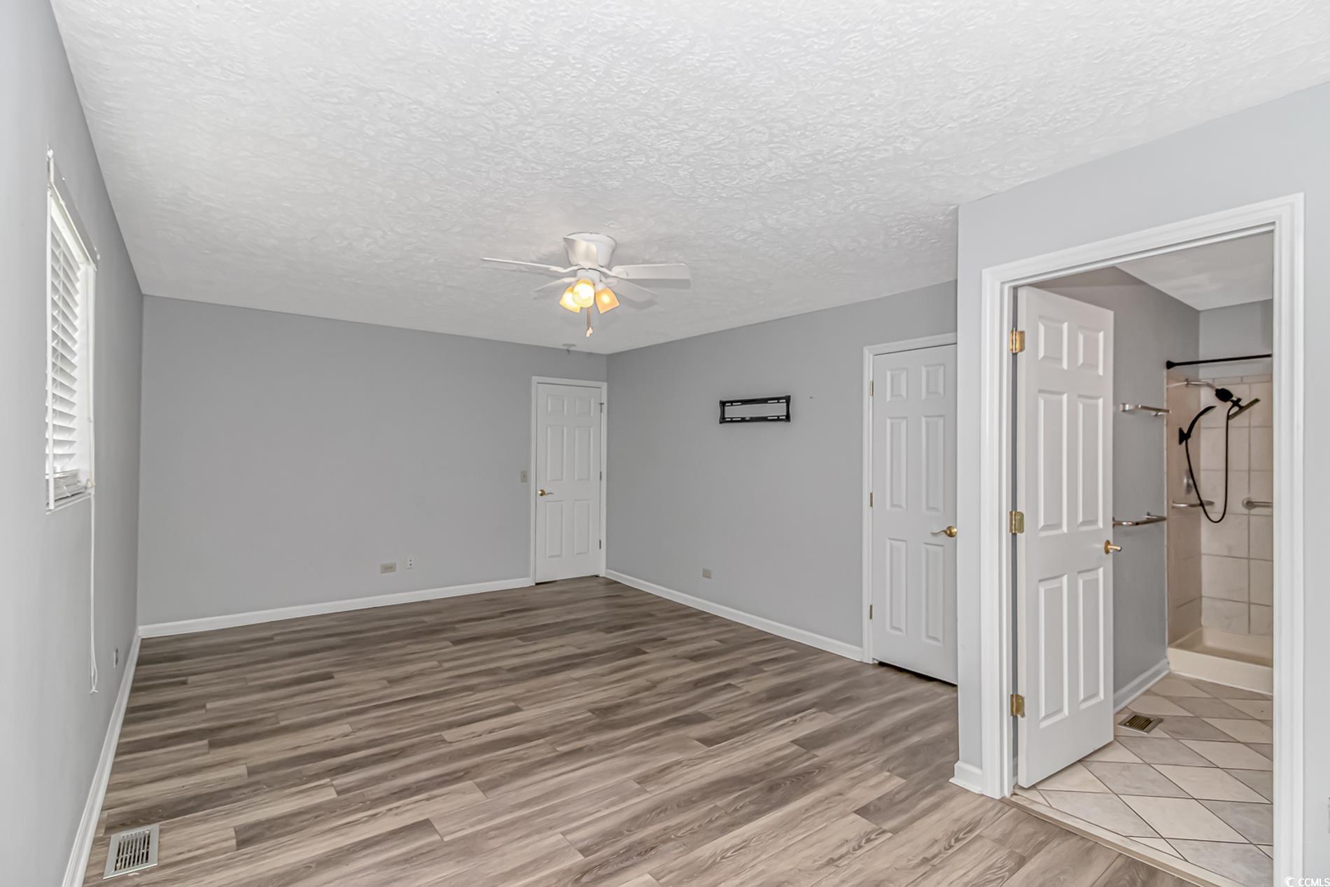 2829 Highway 129 Galivants Ferry, SC 29544 - Photo 18 of 40 Unfurnished bedroom featuring light wood-type flooring, a textured ceiling, a ceiling fan, and ensuite bath