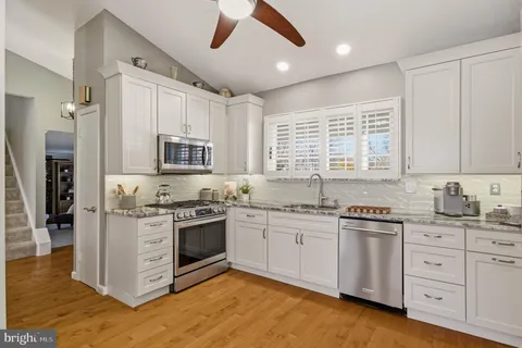 a kitchen with stainless steel appliances granite countertop a refrigerator a sink a stove and white cabinets
