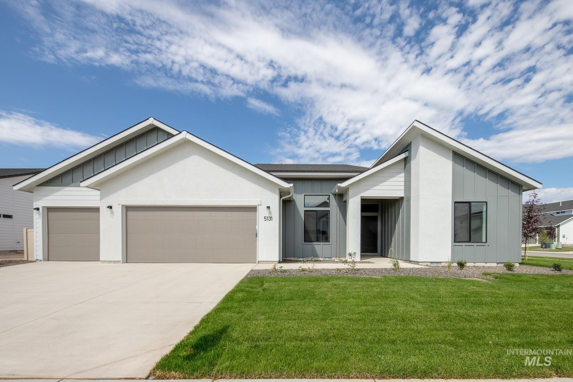 View of front of property with board and batten siding, an attached garage, concrete driveway, and a front yard