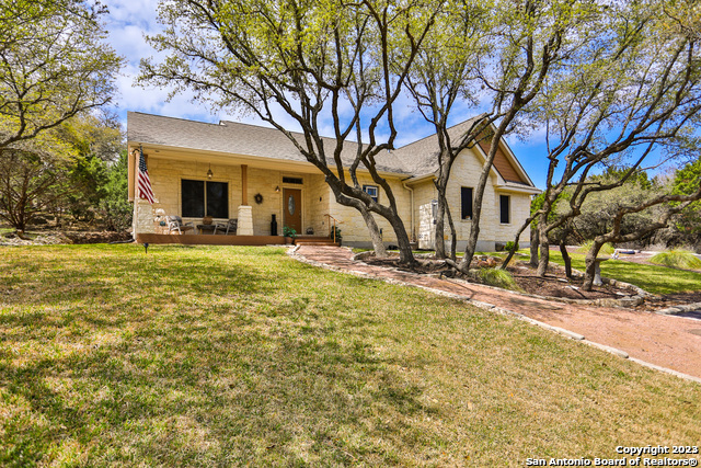 a view of a house with a yard and large tree