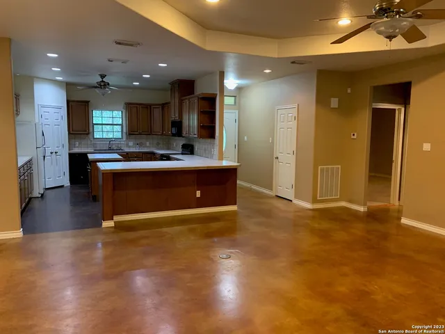 a view of kitchen with kitchen island a sink appliances and a living room