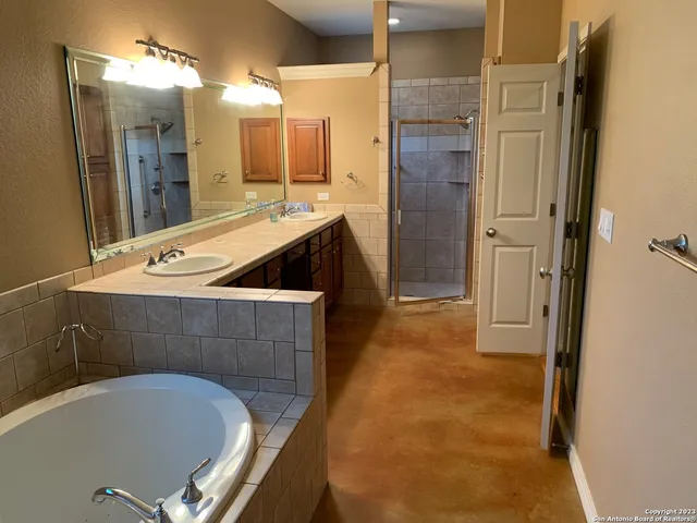 a bathroom with a tub a sink and mirror