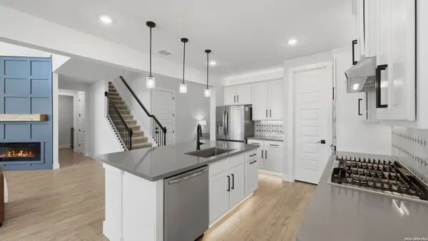 a kitchen with stainless steel appliances granite countertop a sink a stove a refrigerator and a wooden floor