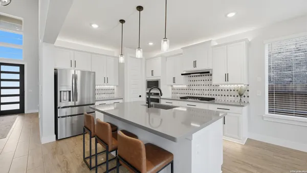 a kitchen with kitchen island a stove a sink a refrigerator and chairs